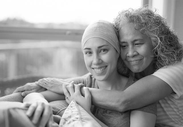 Older woman hugging female cancer patient