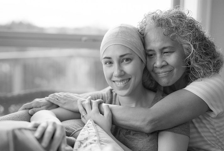 Older woman hugging female cancer patient